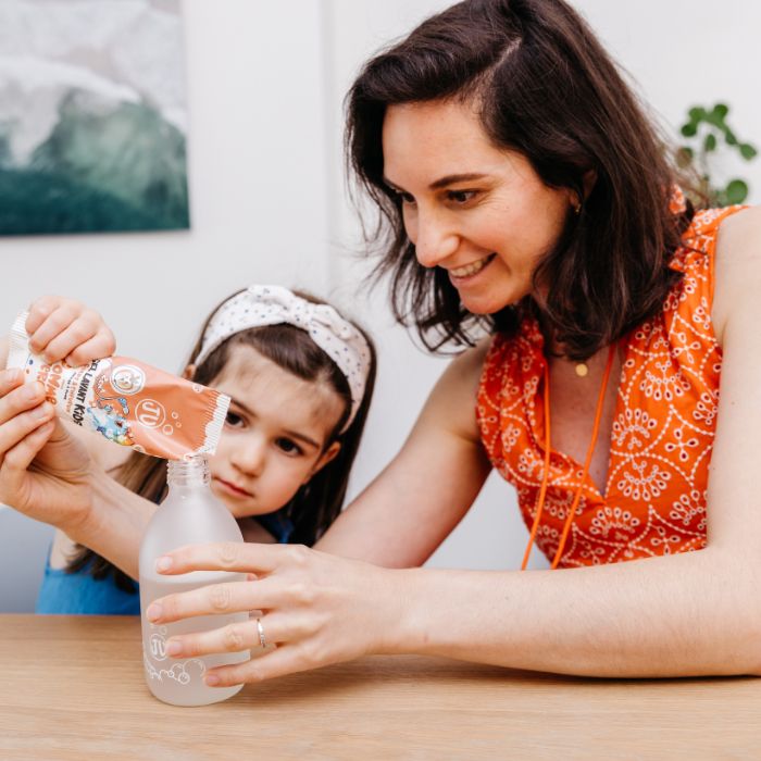 Karline et sa fille versant la poudre de la recharge gel lavant kids dans la bouteille en verre